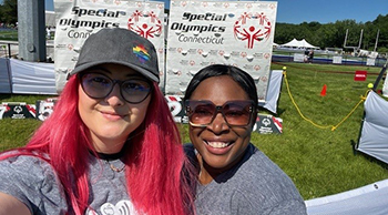 Two helpers take selfie in front of Special Olympics banners