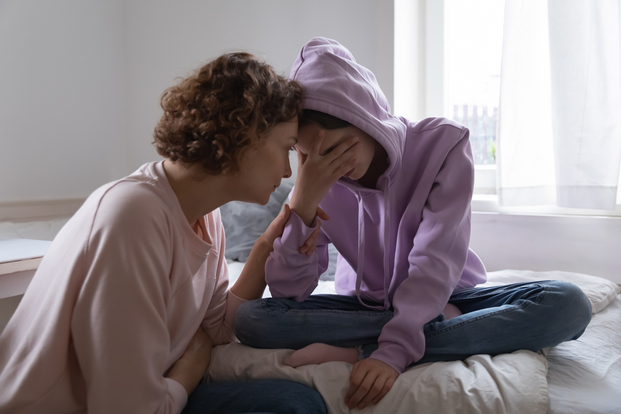 Mother comforting depressed teen